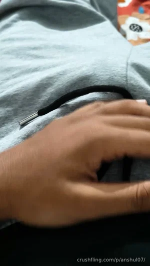Hand resting on gray fabric, black cable visible, colorful patterned object in background.