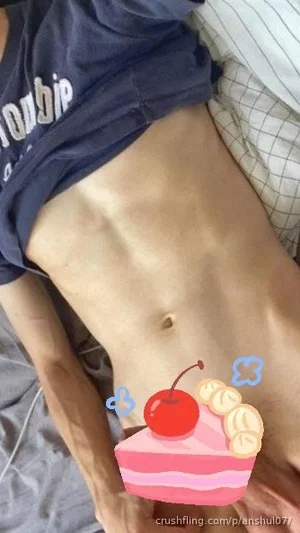 Person with toned abdomen wearing a dark t-shirt, lying on a bed with a cake sticker overlay.