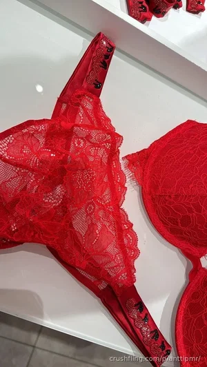 Red lace lingerie displayed on a white shelf, no person visible.
