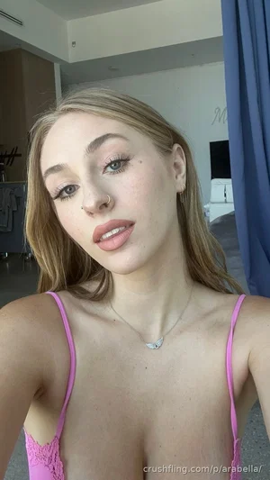Woman with blonde hair in pink lace lingerie, indoors, looking at camera.