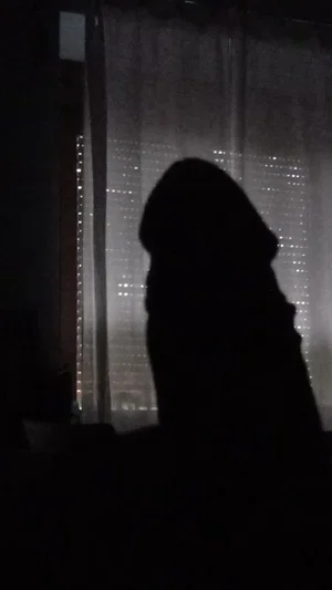 Silhouette of a person in front of a window with city lights at night.