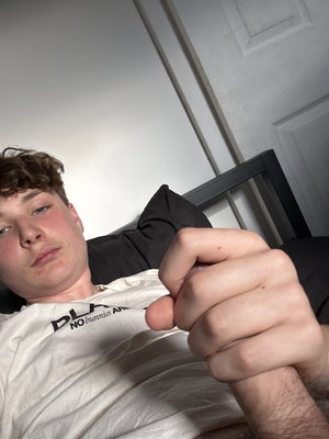 Young man with curly hair in white t-shirt lying on bed.