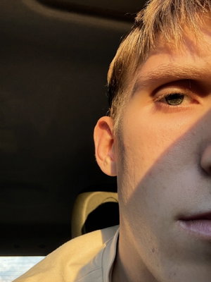Man with light brown hair and stubble in vehicle interior.