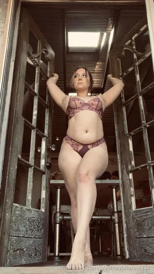 Woman in purple lace lingerie standing in doorway, barefoot, indoor setting.
