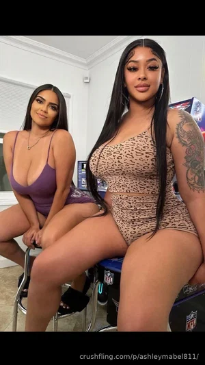 Two women in lingerie posing indoors, one in purple top, one in leopard print set.