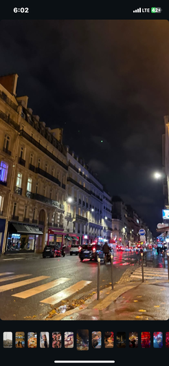 Nighttime city street with wet pavement and buildings.
