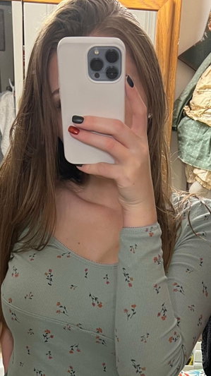 Woman with long brown hair taking mirror selfie indoors.