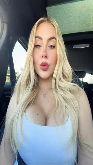 Blonde woman in white tube top in car.