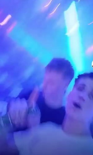 Men in casual clothes dancing in neon-lit club.