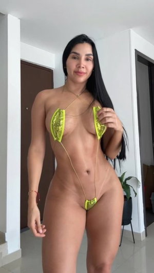 Woman with long dark hair in neon sequin bikini indoors.