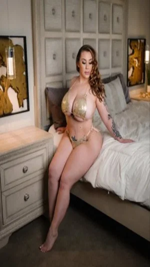 Woman in gold lingerie posing on bed in bedroom.