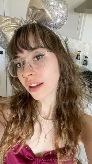 Woman with curly hair, glasses, and sparkly headband in a kitchen, wearing a purple top.
