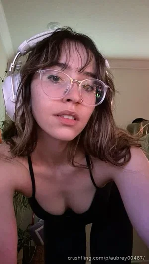 Woman with glasses and headphones wearing black tank top indoors.