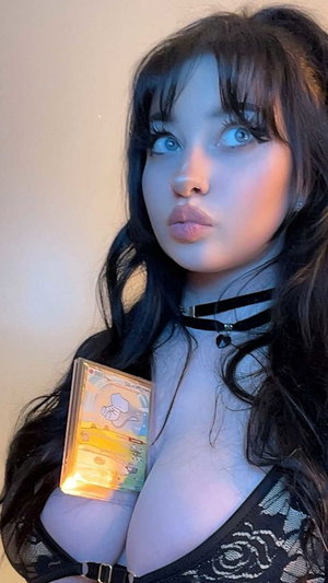 Woman with long dark hair in black lace lingerie holding a card, indoors.