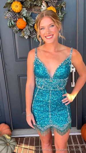 Woman in teal sequined dress standing in front of door with autumn wreath.