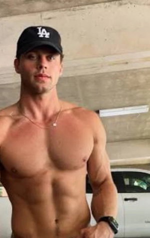 Muscular man in black cap posing shirtless indoors.