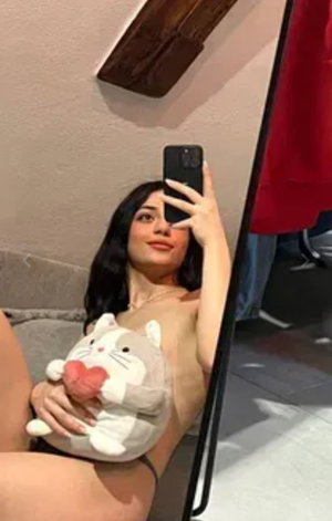 Woman taking mirror selfie holding plush toy indoors.