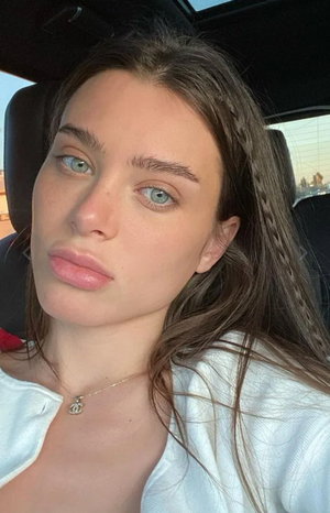 Woman with long brown hair taking selfie in car.