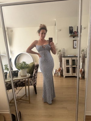 Woman in floral dress taking mirror selfie in living room.
