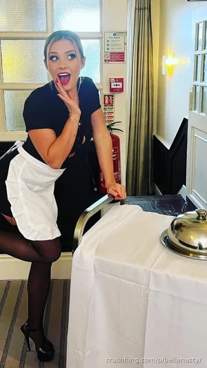Woman in black top and white skirt posing near table in indoor setting.