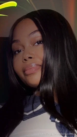 Woman with long black hair wearing a white top with blue details, indoors.