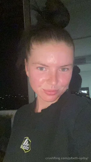 Woman with hair in bun, wearing black Adidas shirt, indoors at night.