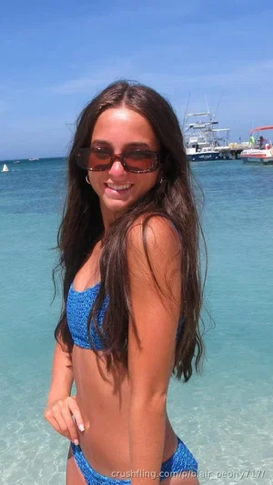 Woman in blue bikini posing by clear turquoise water at beach.