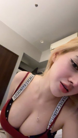 Buxom blonde in red polka-dot top indoors.