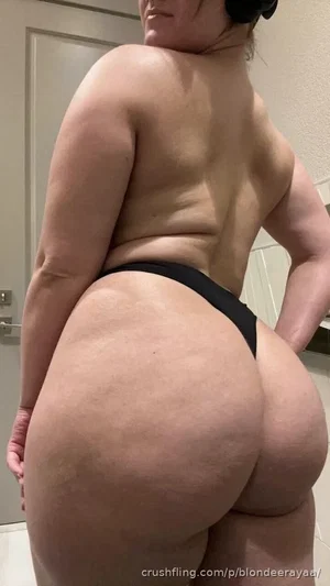 Woman in black thong, back view, indoor setting, wearing headphones.