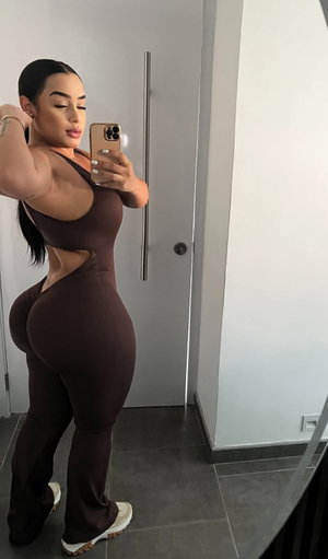 Curvy brunette in brown cut-out bodysuit mirror selfie indoors.