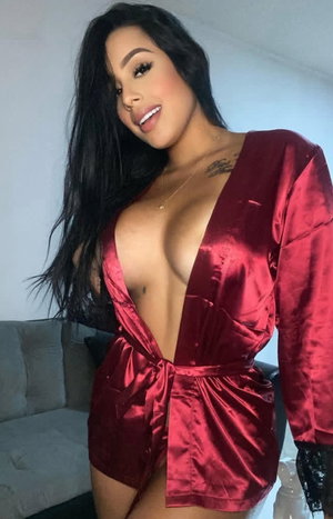 Curvy brunette in open red satin robe indoors.