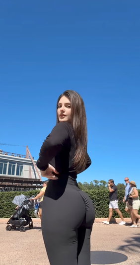Woman with long brown hair wearing black outfit outdoors.
