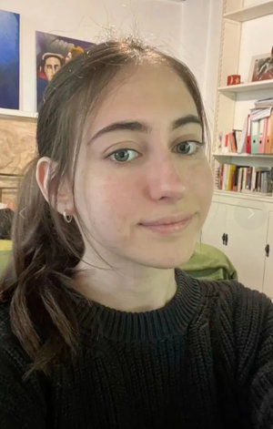 Woman with brown hair in black sweater posing indoors.