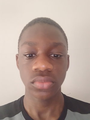 Young Black man in dark shirt taking a selfie indoors.