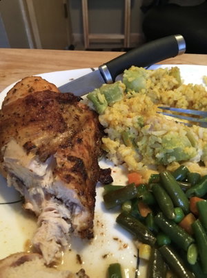 Plate of chicken with rice and vegetables on table.