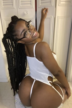 Woman with long braids in white lingerie posing indoors near white doors.