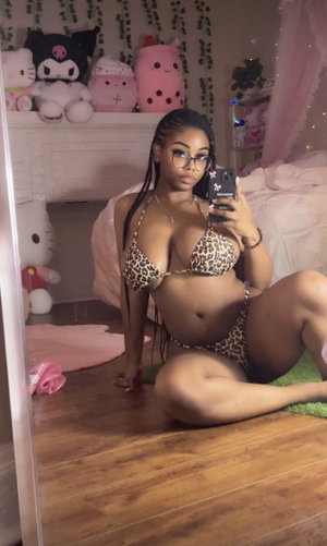 Curvy woman in leopard bikini taking selfie in bedroom.