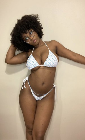 Woman with curly hair in bikini and glasses indoors.