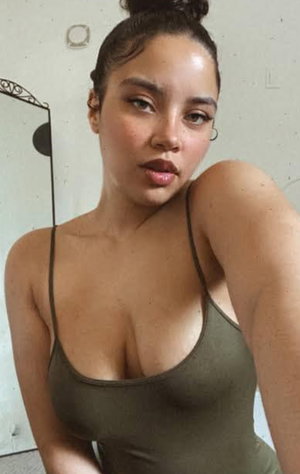 Woman with dark hair in bun wearing green tank top indoors.