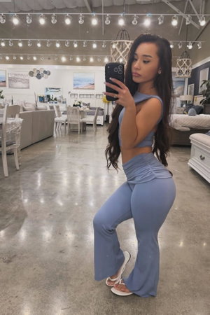 Curvy Asian woman in blue crop top and flared pants in furniture store.