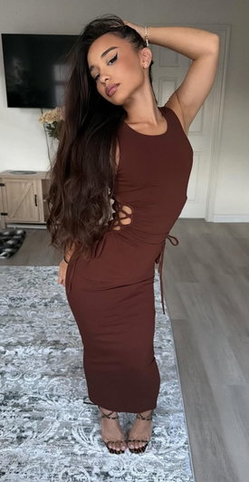 Woman in brown dress posing in living room with long dark hair.