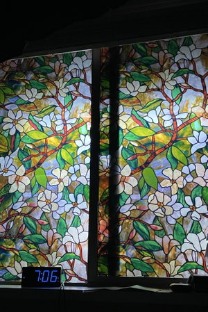 Stained glass floral window with digital clock below.