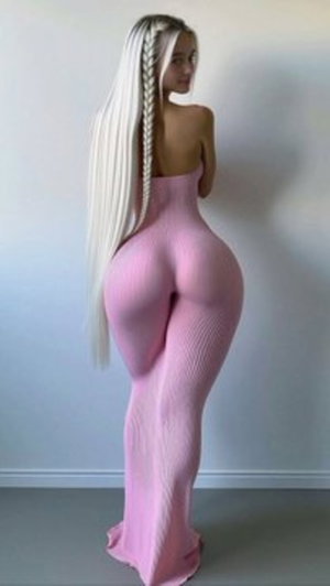 Woman with long blonde braid in pink form-fitting dress, standing indoors facing away.