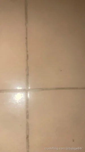 Close-up of beige tiled floor with grout lines and light reflection.