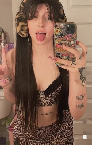 Woman with long dark hair taking mirror selfie in leopard outfit.