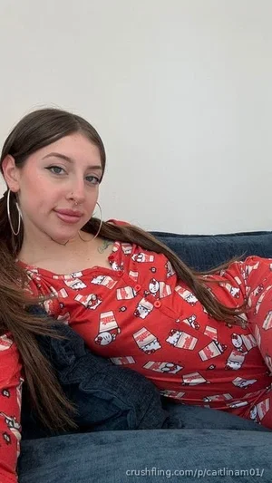 Woman with long brown hair in red patterned top, lying on blue couch indoors.