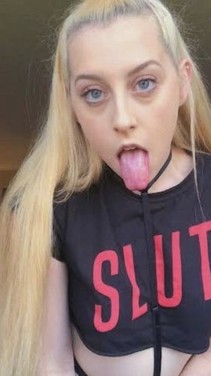 Blonde woman in black crop top sticking out tongue.