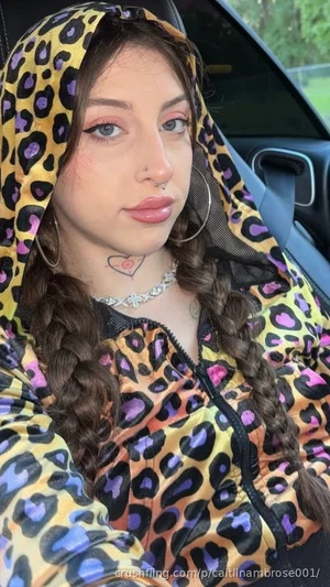 Woman with braided hair in colorful leopard print hoodie, sitting in car.