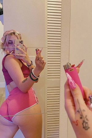 Woman in pink outfit taking mirror selfie indoors.