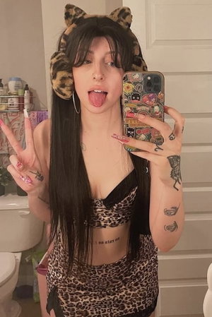 Woman in leopard print taking bathroom mirror selfie.